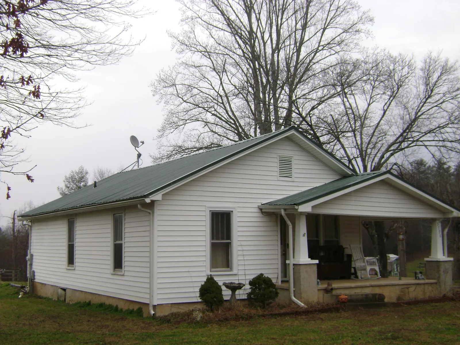 Green metal roof on a white bungalow with a side porch in Greenville